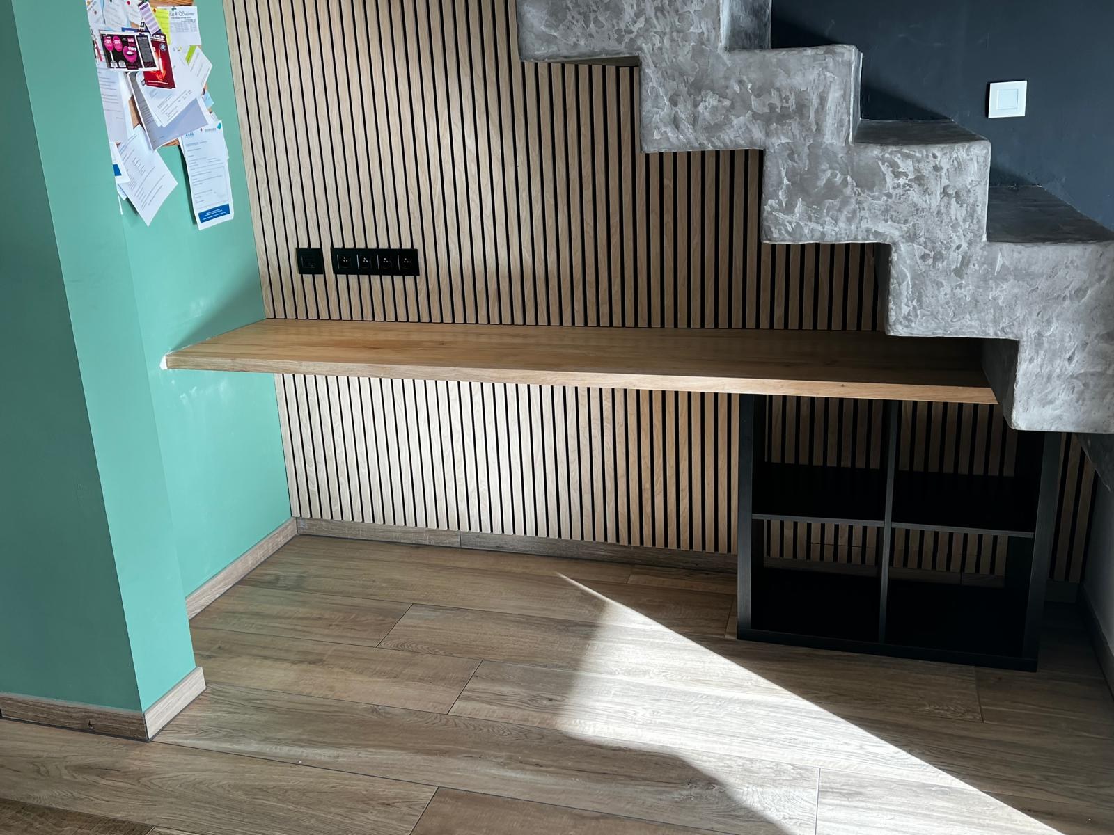 Bureau en chêne installé sous un escalier en béton, avec caisson de rangement en acier noir