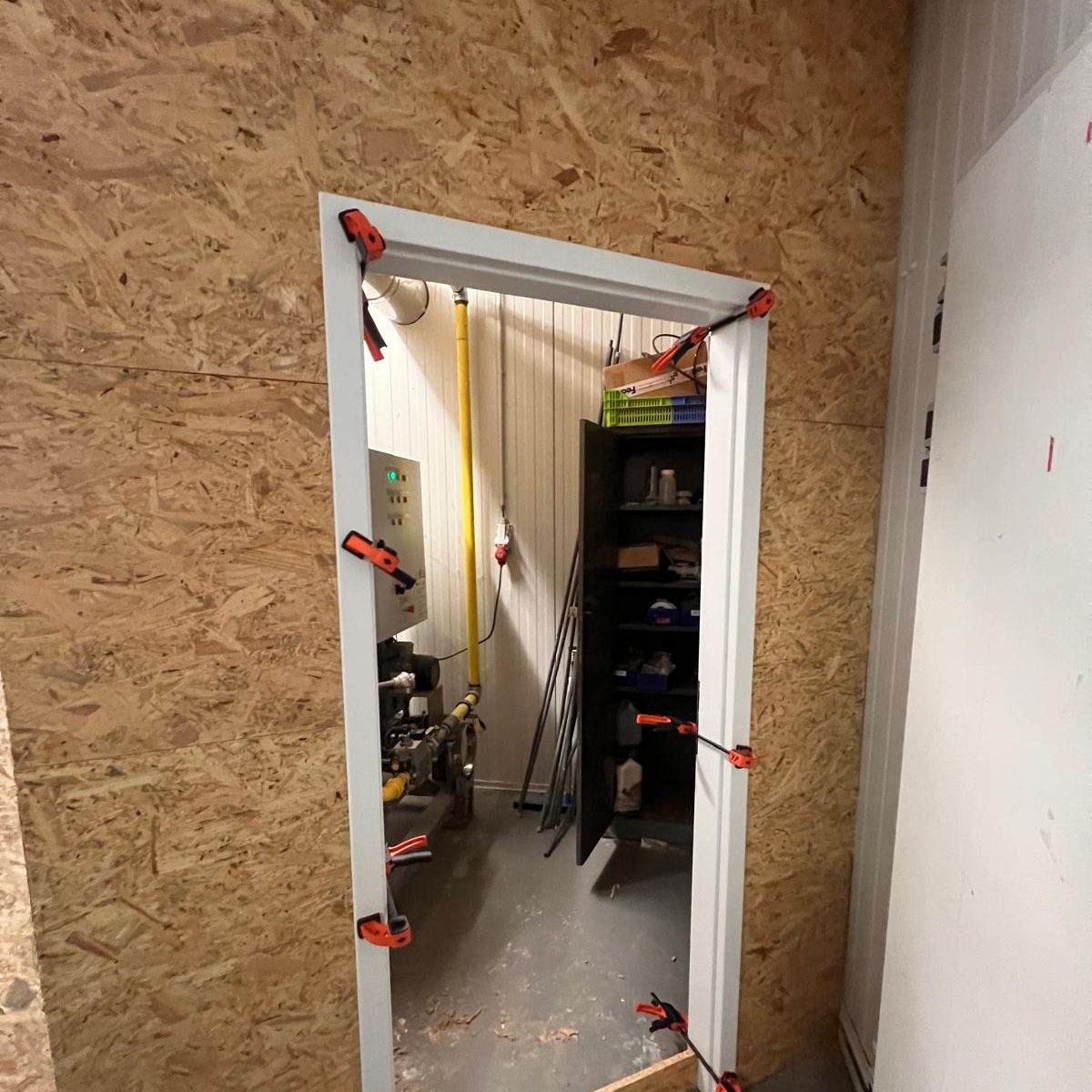 Huisserie de la porte d'accès maintenue à la presse pendant la pose