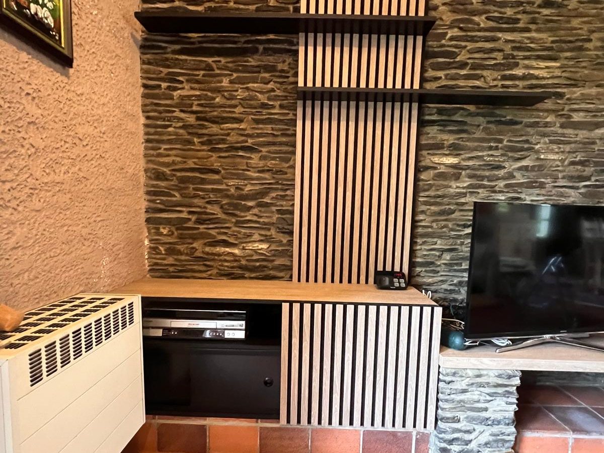 Maison privée — le meuble TV sur mesure terminé contre le mur en pierre